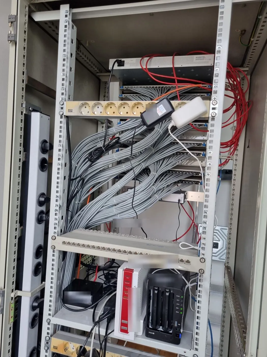 Serverschrank Rückseite nachher: gebündelte Verlegekabel, Steckdosenleiste, Fachboden