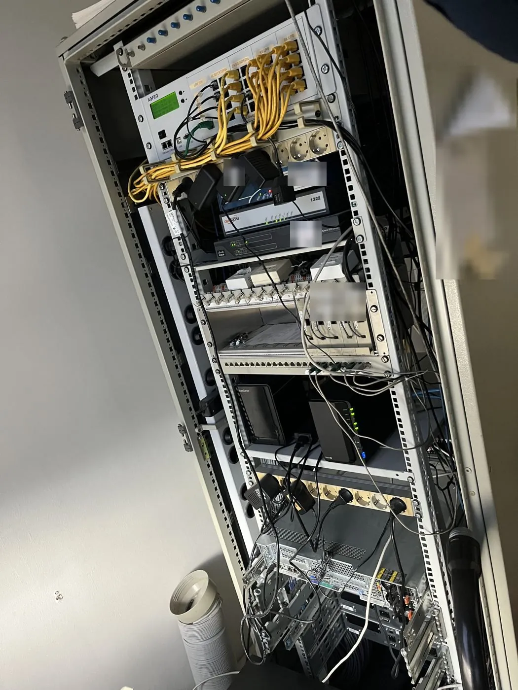 Serverschrank Rückseite vorher: Telefonanlage, lose Netzteile, Patchkabel quer durch den Schrank